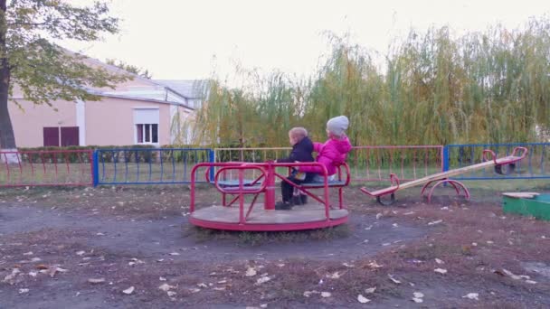 Счастливая девочка и мальчик на карусели — стоковое видео