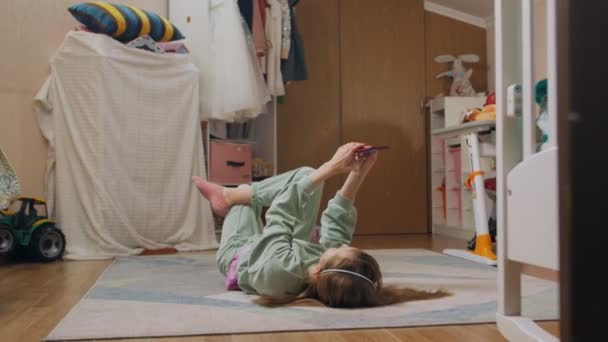 Mädchen mit einem Handy auf dem Rücken liegend — Stockvideo