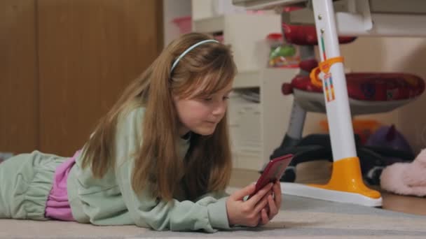 床に横になって電話を持つ女の子 — ストック動画