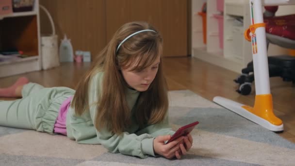 Dívka s chytrým telefonem ležící na podlaze — Stock video