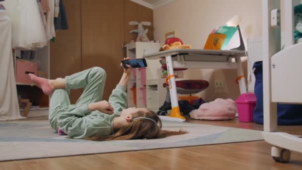 Дівчина з телефоном лежить на підлозі — стокове відео
