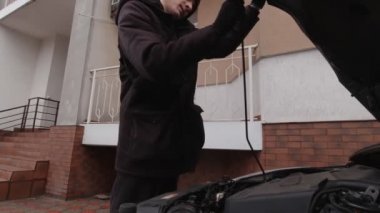 Adamın biri arabadaki yağı kontrol ediyor.