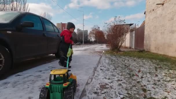 Un niño con un coche de juguete camina al aire libre en cámara lenta — Vídeo de stock
