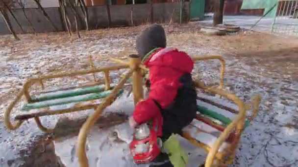 Garçon filer sur un carrousel en hiver — Video