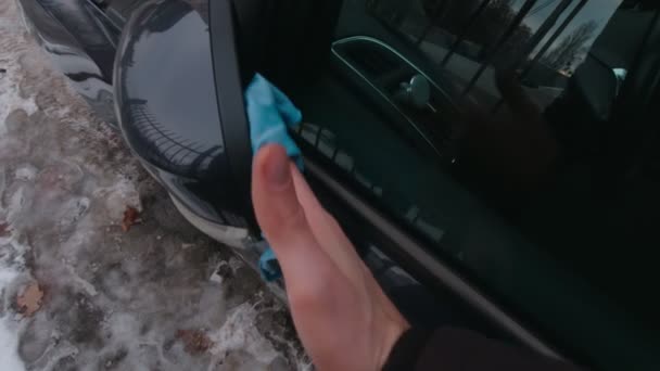 Mann putzt den Rückspiegel eines Autos — Stockvideo