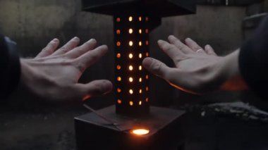 Adam eski sobanın başında ellerini ısıtıyor.