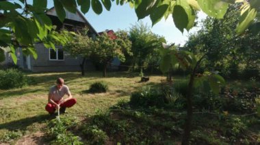 A man sits and waters the garden slow motion sunny summer day