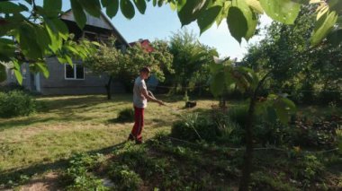 A man waters the plants in the garden slow motion sunny summer day