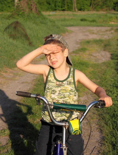 Een jongen op een fiets loensen te bevorderen van de zon Stockfoto