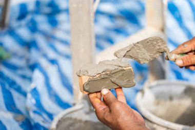 Kil tuğlalara çimento döşeyen işçinin eli tuğla, harç ve macun bıçağıyla duvar ören inşaat işçisi.