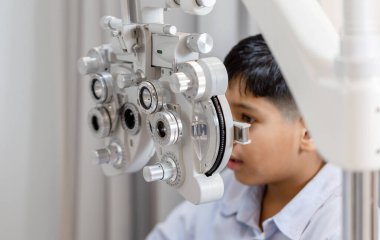 Optik atölyesindeki göz testi yapan bir çocuk, klinikteki çocuk hasta için görme testi yapan bir optometrist.