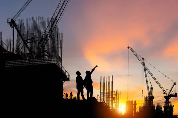 現場のエンジニアと労働者のシルエット 夕方の日没時の建設現場 — ストック写真