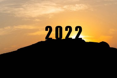 2022 yılının silueti, 2022 yılının hazırlıkları için gün batımı gökyüzü ile birlikte dağın tepesinde.