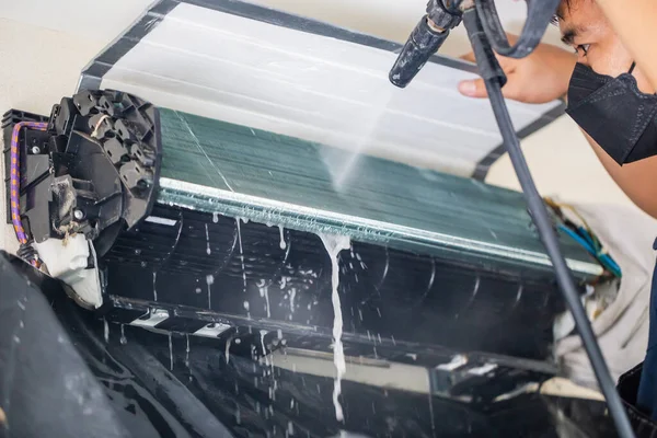 Male technician cleaning air conditioner indoors, Repairman washing dirty compartments air conditioner, Maintenance and repairing concepts