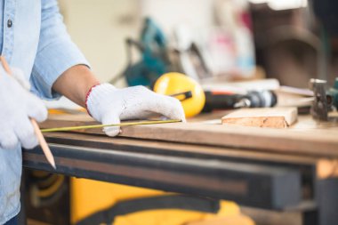 Marangoz ahşap atölyedeki ahşap masada ekipmanla çalışıyor, marangozhanede marangozluk yapıyor.