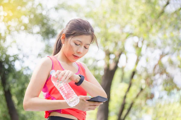 Ung Vacker Kvinna Med Plast Vattenflaska Ser Smartwatch Och Smartphone — Stockfoto