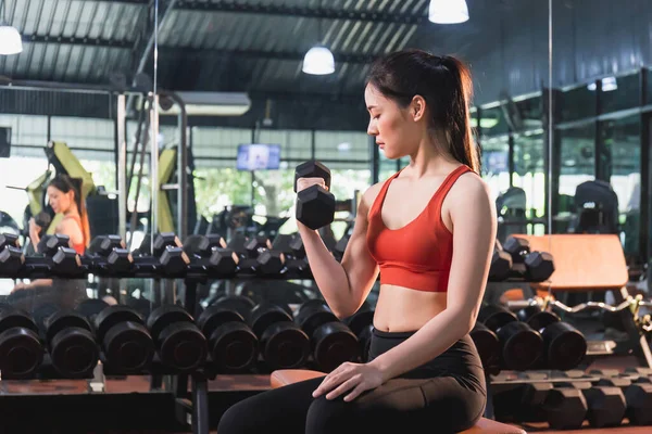 Kol halterleriyle egzersiz yapan genç bir kız spor salonunda halterini kaldıran bir kadın.