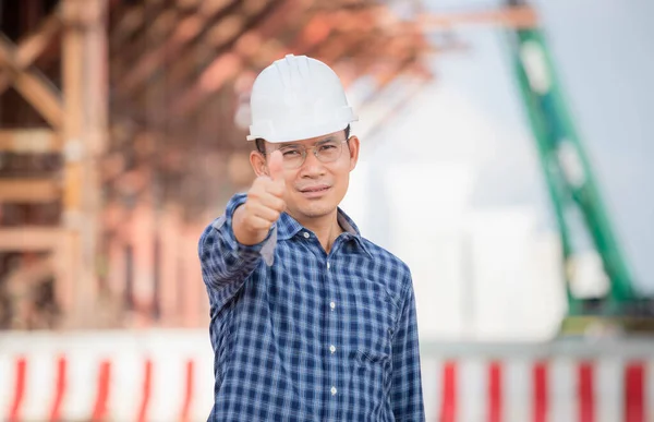 Man in hardhat showing thumbs up at infrastructure construction site, Engineer checking project at the building site