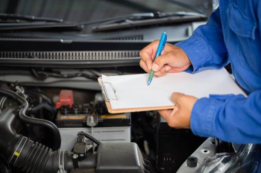 Auto mechanic holding clipboard checklist the car at mechanic shop, Mockup blank clipboard, Technician doing the checklist for repair machine a car in the garage clipart
