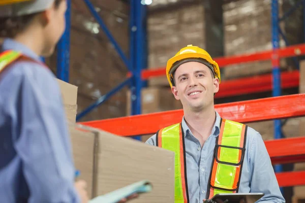 Manager and supervisor taking inventory in warehouse, Female foreperson making plans with warehousemen, Workers working in warehouse