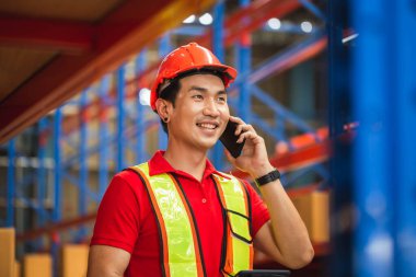 Akıllı telefon ve dijital tabletle depoda çalışan neşeli bir depo çalışanı depoda çalışan bir işçi.