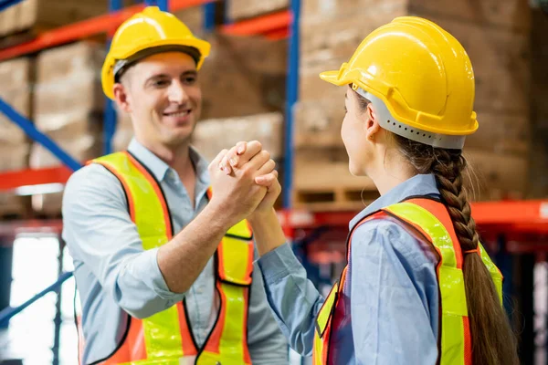 Warehouse workers soul brother handshake, thumb clasp handshake or homie handshake with blurred factory warehouse background, Success and Teamwork concepts