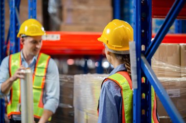 Selective focus worker team wrapping boxes in stretch film at warehouse, Worker wrapping stretch film parcel on pallet in factory warehouse