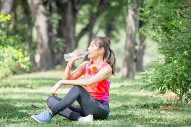 Yeşil Park 'ta plastik şişeden su içen genç ve güzel bir sporcu kadın spor yaptıktan sonra su içiyor.