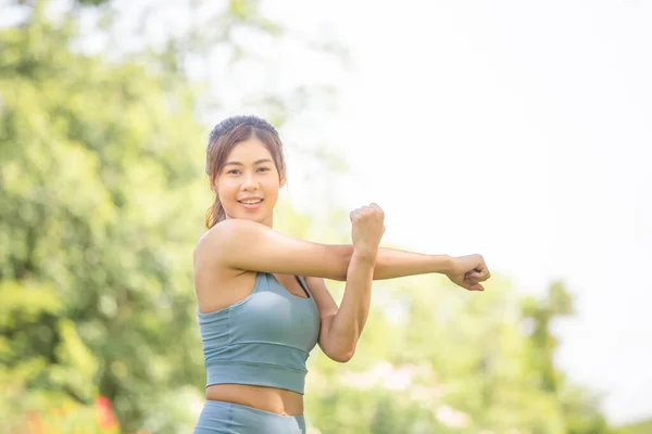 健康女性在运动前伸展肌肉 女性在公园晨练时伸展肌肉 年轻女性在运动前伸展双手 准备跑步 — 图库照片