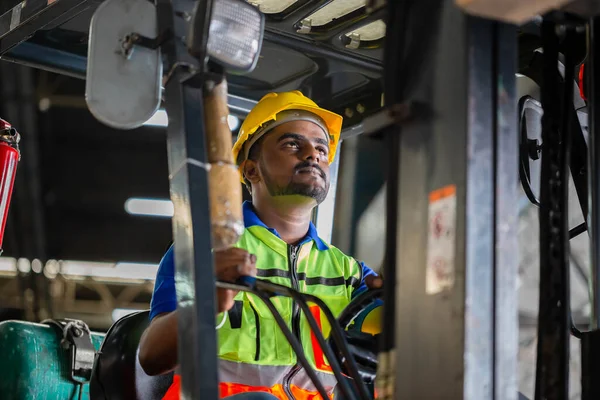 Depodaki forklift yükleme kutusunu kontrol etmek için çelik yelek ve çelik yelek giyen işçi mallarla çalışır.