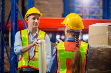 İşçi takımı depoda streç film kutularını paketliyor, işçiler fabrika deposunda streç film paketlerini palete sarıyorlar.