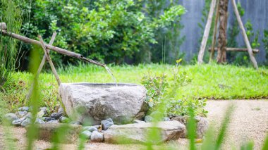 Japon bahçelerindeki bambu çeşmesi bulanık arkaplan, su akışlı geleneksel Asya bambu çeşmesi