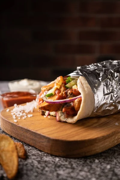 Taze sebze ve et çukurunda bir shawarma. Büyük baharatlarla. Restoran servisi. Karanlık bir arka planda. Menüler ve reklamlar için