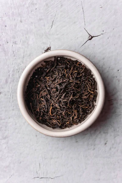 selective focus, natural black leaf tea. brewing in a clay bowl. vertical angle, macro. on a light background. for menus and cafes