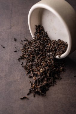 Seçici odaklanma, doğal siyah yaprak çayı. Kil kasesinde demleniyor. Dikey açı, makro. Karanlık bir arka planda. Menüler ve kafeler için