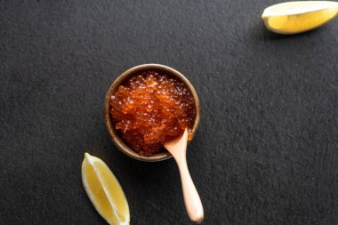  Koyu arka planda tahta kaşıkla seramik bir kasede taze kırmızı havyar. kopyalama alanı