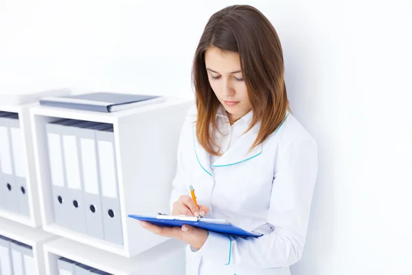 Portret młodego lekarza kobiece pisanie w schowku w szpitalu — Zdjęcie stockowe