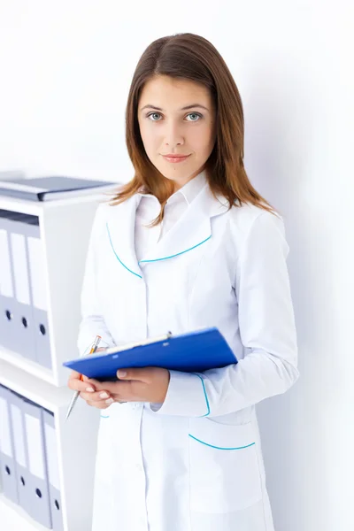 Portrait of young female doctor holding clipboard in hospital — Stock Photo, Image