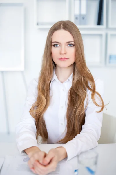 Retrato de una hermosa joven mujer de negocios sentada en el escritorio en br — Foto de Stock