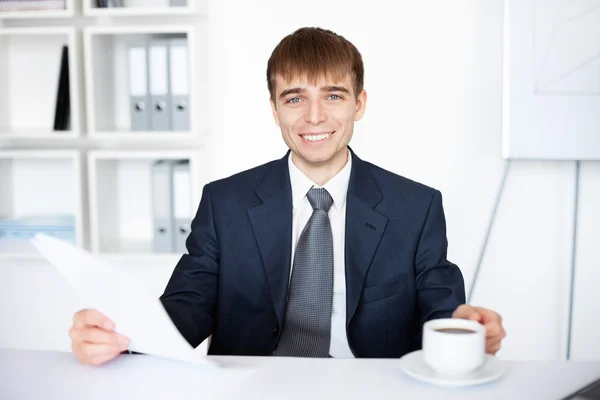 Portret młodego biznesmena trzymając kubek kawy i dokumenty — Zdjęcie stockowe