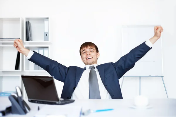 Расслабленный счастливый молодой бизнесмен после работы в офисе — стоковое фото