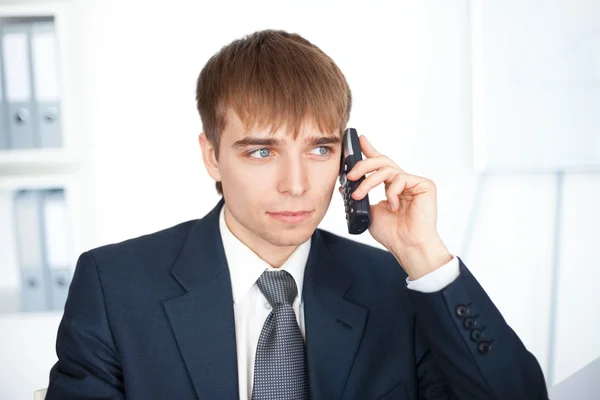 Ung affärsman talar i mobiltelefon i office — Stockfoto