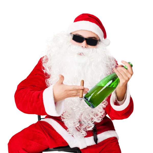 Le Père Noël assis sur une chaise portant des lunettes de soleil tient une bouteille — Photo
