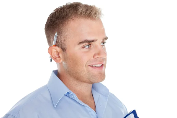 Młody uśmiechnięty człowiek biznesu z pióra za uchem na białym tle — Zdjęcie stockowe