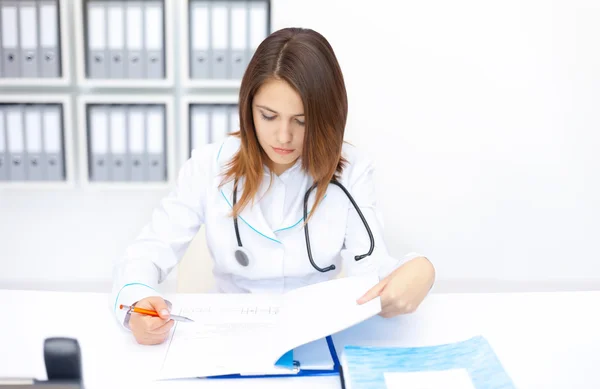 Jonge vrouwelijke arts doen sommige papierwerk in ziekenhuis — Stockfoto