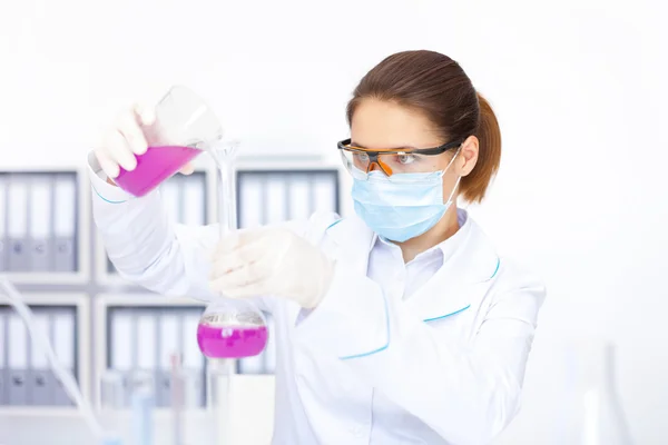 Молодая женщина-исследователь разливает химикаты — стоковое фото