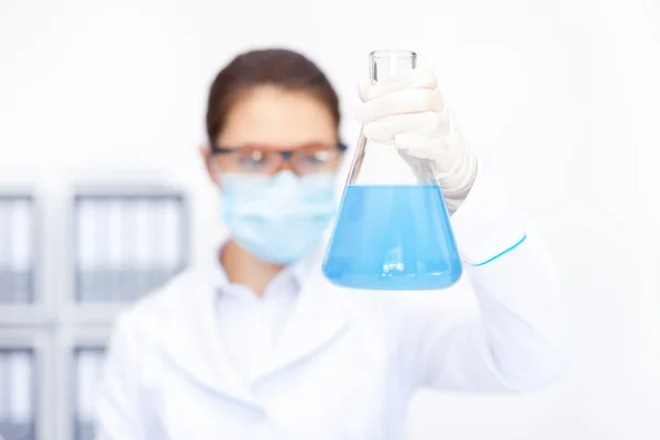 Female researcher observing liquid in flask — Stock Photo, Image