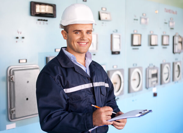 young smiling engineer taking notes at control room