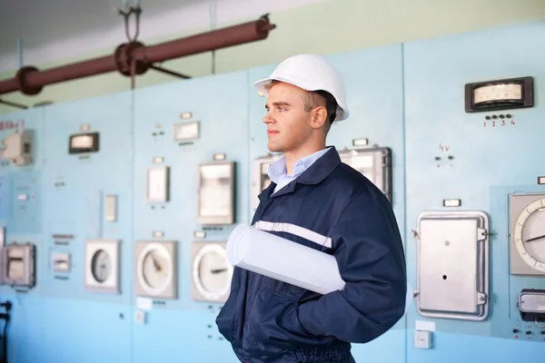 Engenheiro com capacete e plantas na sala de controle — Fotografia de Stock