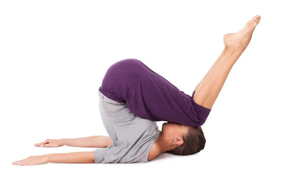 Ung kvinna gör yoga motion Halasana (plog utgör) — Stockfoto